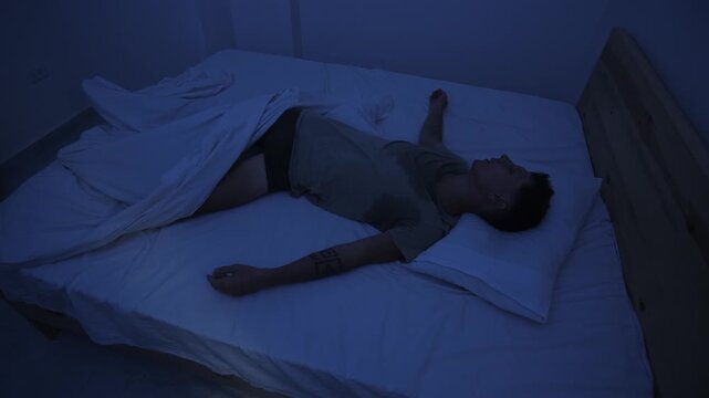Sweating man tossing and turning in bed, restless and unable to sleep because of extreme heat at night