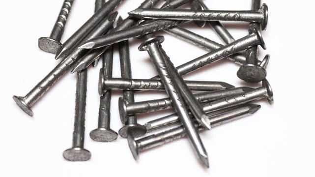 A pile of nails sitting on a white surface, ready for use. Rotating in a circle