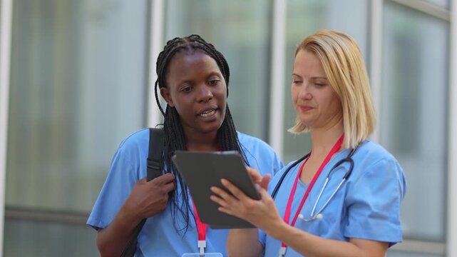 Two female medical professionals collaborating on a digital tablet