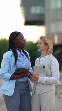 Multiethnic businesswomen talking while holding tablets in the city