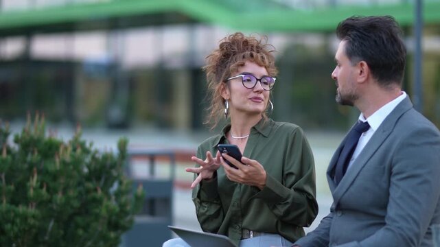 Business colleagues discussing a project on a smartphone