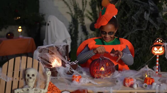 Girl in pumpkin costume playing with a halloween decoration