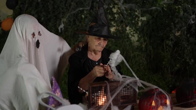 Senior woman in a witch costume preparing Halloween decorations