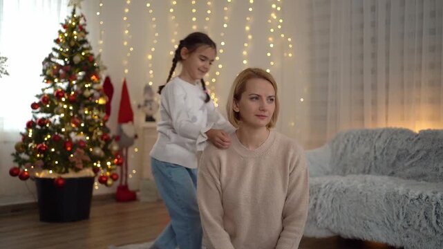 Daughter surprisingly hugging her pensive mother on christmas eve