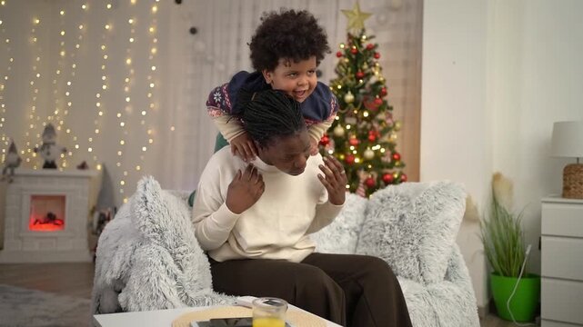 Playful african american boy hugging his mother on christmas eve