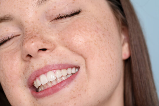 Beautiful teenage girl with freckles on light blue background, closeup