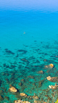 Persona su stand up paddle nel mare cristallino e turchese di Tropea