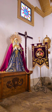 Mourning Virgin Mary sculpture beside a processional banner inside Iglesia Parroquial de San Pablo, Baeza, Ja&eacute;n province, Andalusia, Spain.