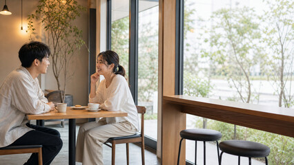 Obraz premium 窓際のカフェで穏やかに会話を楽しむ休日の若いカップル