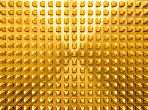 Full frame close up view of golden brass metal surface featuring 3D studded pyramid spike grid pattern for luxury background and abstract texture design