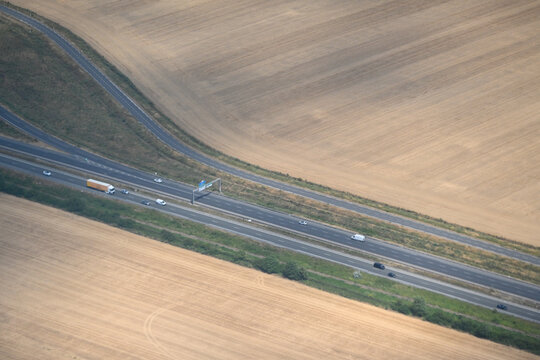 Aerial view of a highway crossing agricultural fields near Paris. Road traffic and transport infrastructure through rural farmland in France.