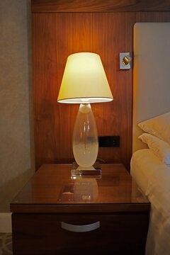 Bedside table with lamp and part of the bed in soft lighting