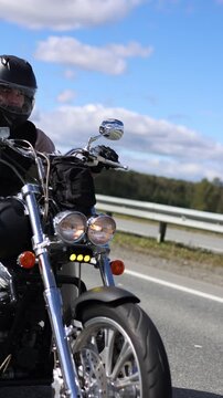 A motorcyclist rides his motorcycle on an asphalt road. Headwinds and the spirit of travel. Freedom and speed. Slow motion vertical footage.