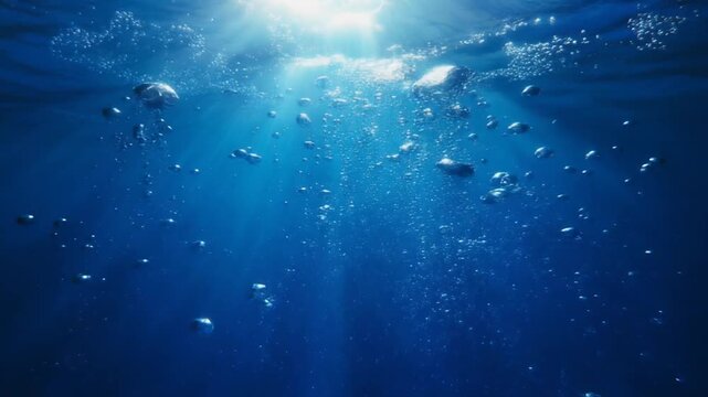 Underwater ocean scene with sunlight streaming through the water surface and small fish swimming in deep blue sea