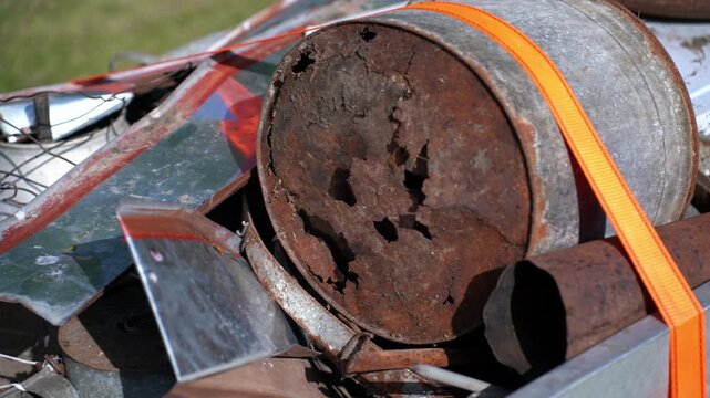 Slow pan shot, trailer loaded with scrap metal, secured with orange ratchet straps, transporting to the scrapyard for recycling.