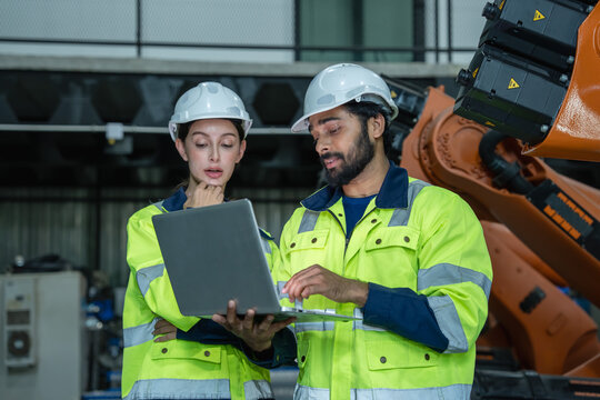 Engineers collaborating on robotics project in modern industrial environment with advanced technology