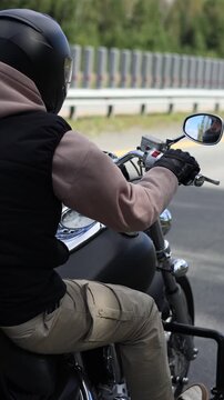 Back view of a motorcyclist rides his motorcycle on an asphalt road. Headwinds and the spirit of travel. Freedom and speed. Slow motion vertical footage.