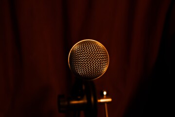 Professional microphone on stage with dark red curtain background in spotlights © Nazar