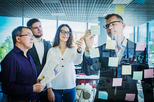 Business Team Brainstorming with Sticky Notes on Glass Wall