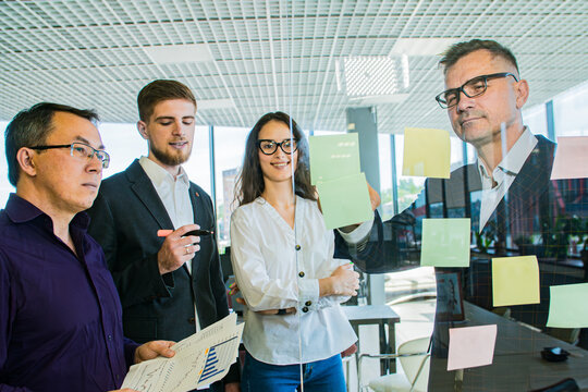 Business Team Brainstorming with Sticky Notes on Glass Wall