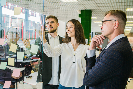 Business Team Brainstorming with Sticky Notes on Glass Wall