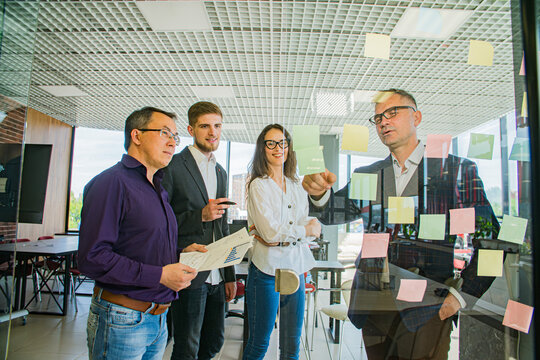 Business Team Brainstorming with Sticky Notes on Glass Wall