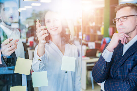 Business Team Writing Ideas on Glass Board Through Reflection