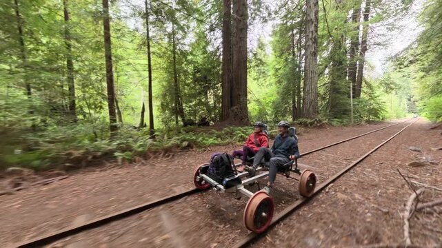 Couple enjoys an adventure on an electric railbike over old railroad tracks in a redwood forest near Fort Bragg California.