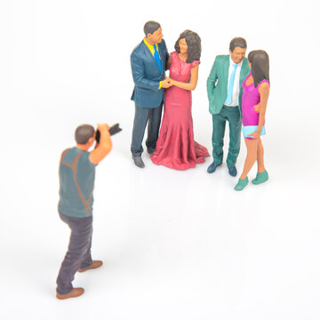 Miniature people gathered for a photo shoot with a photographer taking pictures at a simple backdrop