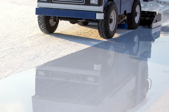 Ice resurfacing machine works on rink during afternoon in outdoor location
