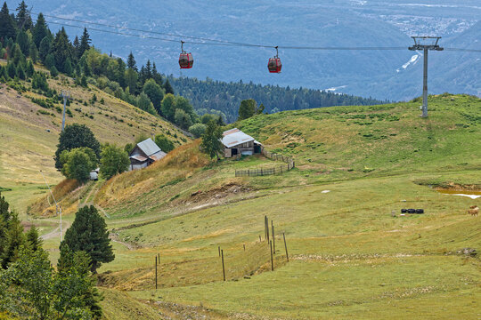 Two faces of mountain, with meadows and farms under a cable-car for tourists