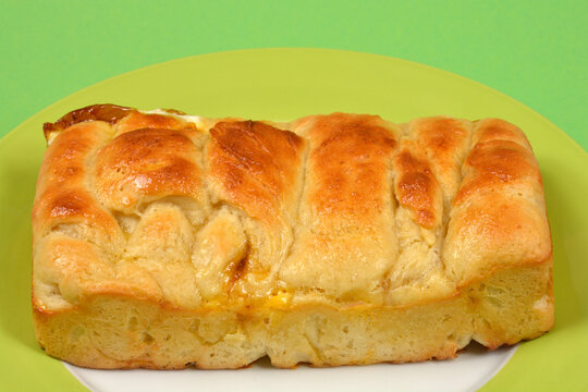 A high angle view of a rectangular loaf of golden brown freshly baked brioche bread served on a round plate with a green rim.