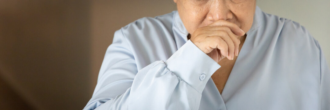 Sick and allergic old Asian senior woman suffering from runny nose, concept image for cold, flu, viral infection, dust or pollen allergy, indoor scene, nose sniffle closeup shot