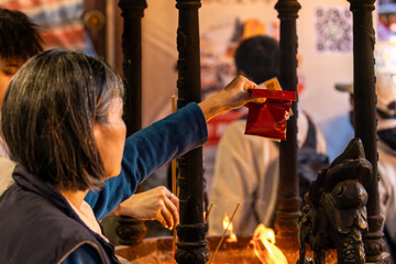 Obraz premium Worshipper Purifies Red Packet Over Temple Flame