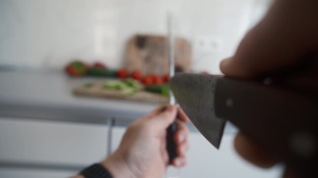 Hands Sharpening A Large Kitchen Knife With A Sharpener Before Preparing A Salad, Object POV camera angle shot