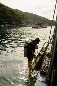 Woman scuba diver climbing ladder onto dive boat in Thailand