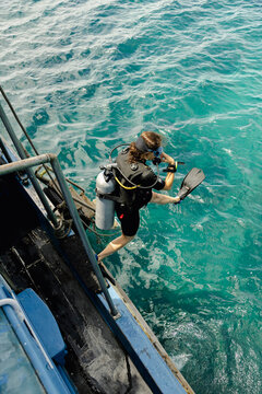 Woman scuba diver jumping from dive boat into tropical water