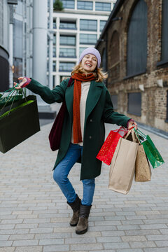 Happy woman holding gift bags enjoying winter shopping
