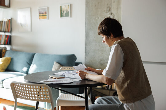 Side back view of young pretty woman checking financial documents