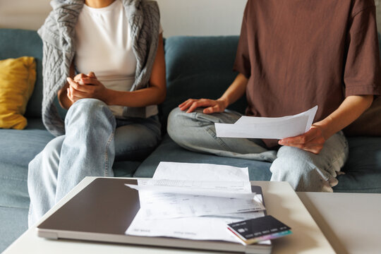 Partial view of women checking financial documents on sofa at home