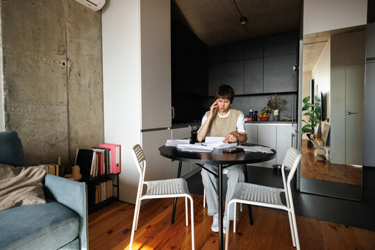 Young sad and thoughtful woman checking financial documents at desk