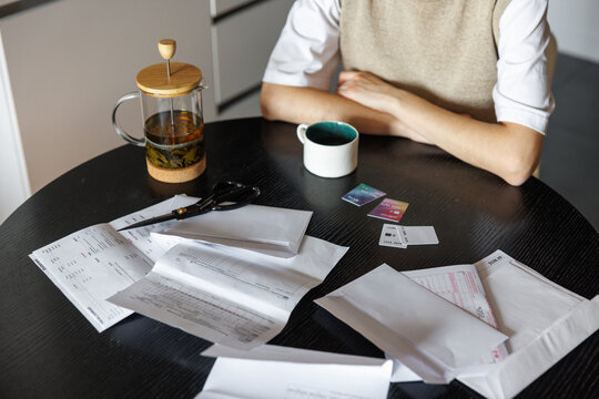 Partial woman at desk with tea, credit cards, documents and scissors