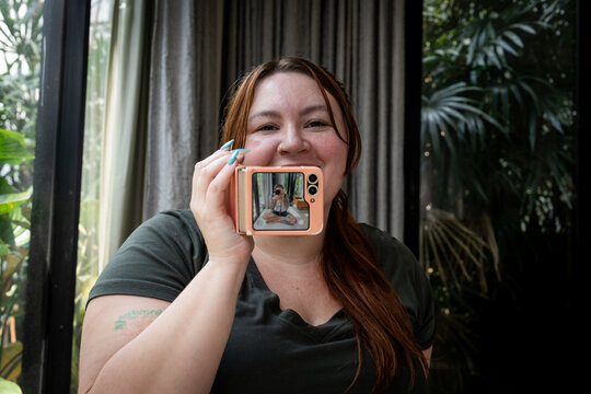 A plus-size Gen Z girl with bangs takes a photo of a photographer