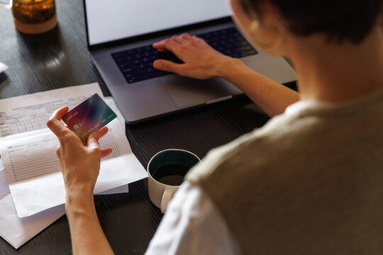 Cropped woman paying with credit card on laptop at desk