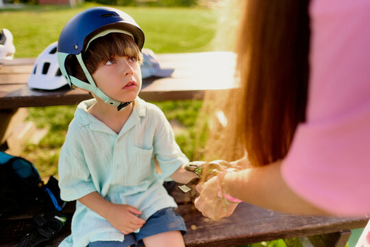Mother Fastening Protective Gear for Young Son