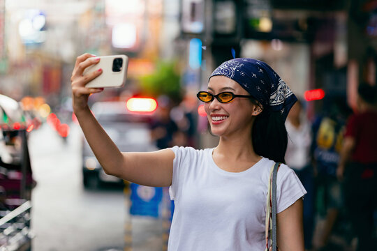Smiling Woman Taking Selfie On Busy City Street
