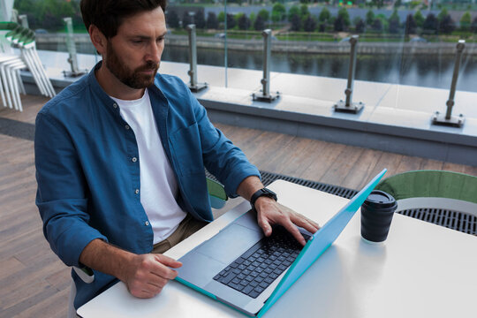 Man Working on Laptop at Outdoor Cafe