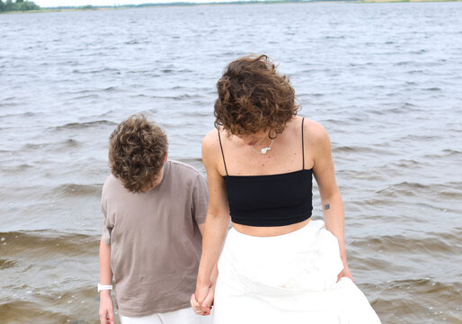 A mother and son are walking by the river.