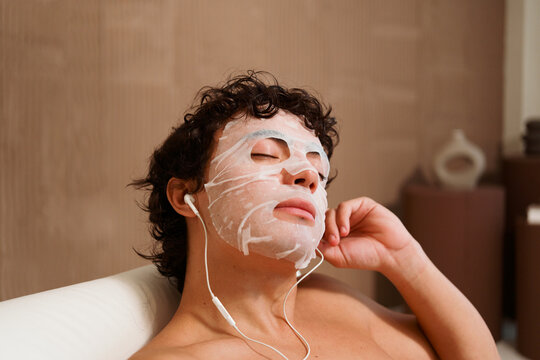 Man Relaxing With Facial Mask and Earphones at Home