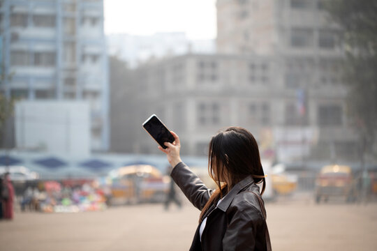 Beautiful Woman taking selfie with smartphone in the street of city